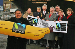 Photograph of a lady holding a giant fairtrade banana with Bristol council members in the background